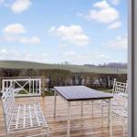 Terrace with table and chairs offers view of fields.