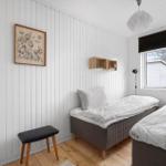 Two beds, wall art, wooden floor, and window with view outside.