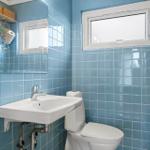 Bathroom with blue tiles, sink, and toilet.