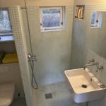 Shower with showerhead, sink, and toilet. Wall and floor tiles.