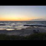 Sunset at the beach with boats and waves