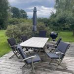 Deck with table, six chairs, umbrella, and grill.