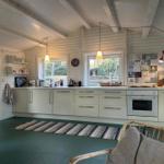 Kitchen with white cabinets, windows, and refrigerator. Wooden floor and rug.