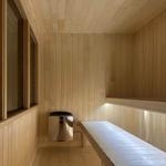 Sauna with wooden cladding, bench, and stove.