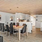 Essbereich mit Tisch, Stühlen und Küchenbereich unter Holzdecke.
