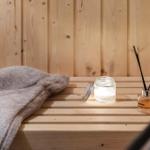 Holzbank mit Handtuch, Duftkerze und Duftdiffusor in Sauna.