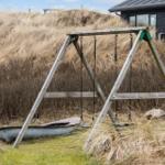 Schaukel im Gras vor einem Haus mit Dach und Fenstern.