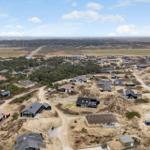 Aerial view of a coastal village with scattered houses and dunes.