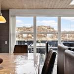 Esszimmer mit Holztisch, Stühlen und Blick auf Grashügel.