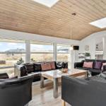 Wohnzimmer mit schwarzen Ledermöbeln, Holzdecke und großem Fensterblick