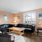 Wohnzimmer mit schwarzen Ledersofas, Holztisch und Fenster.