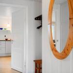 Hausgang mit runden Holzspiegel, Kleiderständer und Blick in die Küche.