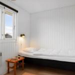 Schlafzimmer mit Bett, Fenster und Holztisch.