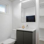Badezimmer mit Toilette, Waschbecken und Spiegel. Fenster und Regal sichtbar.