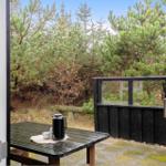 Terrasse mit Tisch und Kanne, Blick auf Nadelbäume