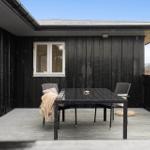 Terrasse mit Tisch und Stühlen vor schwarzem Holzhaus