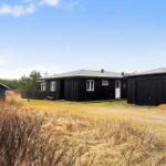 Schwarzes Holzhaus mit Garage und kleinem Nebengebäude auf grünem Grundstück.