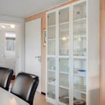 Esszimmer mit Glasvitrine, schwarzen Stühlen und Holzwand.