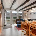 Wohn- und Essbereich mit Holztreppe, Sofa, Esstisch und Fenster zur Außentür.