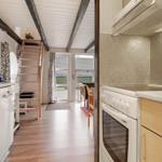 Küche mit Spüle, Herd und Kühlschrank. Treppenhaus führt zu oberem Stockwerk.