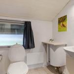 Badezimmer mit Toilette, Waschbecken und Fenster mit Vorhängen.