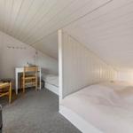 Schlafzimmer mit Doppelbett, kleinem Schreibtisch und Stuhl unter schrägem Dach.