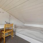 Ein Schlafzimmer mit Doppelbett, Schreibtisch und Stuhl unter schrägem Dach.