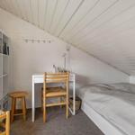 Ein Schlafzimmer mit Dachschräge, Bett, Schreibtisch und Stuhl.