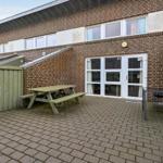 Terrasse mit Picknicktisch, Tisch und Stühlen vor einer Wohnung mit Glasfront.