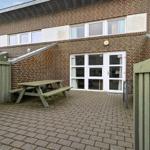 Haus mit Terrasse, Tisch und Gartenzaun. Eingangstür mit Nummer C1.