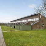 Einfamilienhaus mit Garten und Terrasse. Holztor und Zufahrtsweg sichtbar.