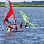 Zwei Windsurfer auf einem See mit grüner und roter Segel.