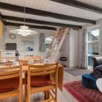 Essbereich mit Tisch, Stühlen und Fernseher. Wohnbereich mit Sofa und Kissen. Treppenhaus zur oberen Etage.