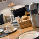 Tisch mit Tassen, Tellern, Brotkorb und Thermoflasche