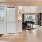 Apartment with kitchen, living room, and wood stove. Wooden floor and large windows.