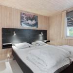 Bedroom with wooden walls, bed, and window overlooking greenery.