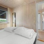 Bedroom with bed, wooden walls, and view into the living room.