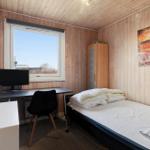 Bedroom with bed, desk, and window. Wooden walls and wall art.