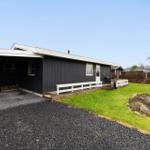 A black house with a white porch and garden.