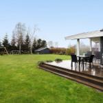 Deck with grill and table. Lawn with playground and shed.