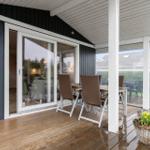 Deck with table, chairs, and flower basket. Sliding glass door leads into the house.