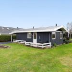 A dark blue holiday home with a white balcony and green lawn.