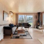 Living room with wood walls, sofa, fireplace, and large windows.