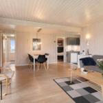 Living room with dining area and kitchen. Wooden ceiling, sofa, coffee table, and artwork.
