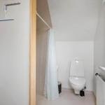 Badezimmer mit Toilette, Duschvorhang und Fenster mit Pflanze.