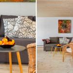 Wohnzimmer mit grauem Sofa, Holzdecke und Korbstühlen. Tisch mit Obst und Wandbild.