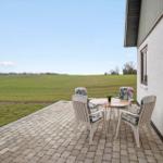 Terrasse mit Tisch und Stühlen, Blick auf grünes Feld.