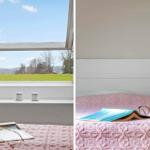 Dachfenster mit Blick auf Feld. Bett mit rosa Decke und Brille.