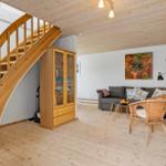Wohnzimmer mit Holzdecke, Sofa, Stühlen und Treppe.
