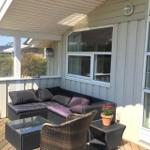 Deck with seating group, table, and plant in front of house wall with windows.